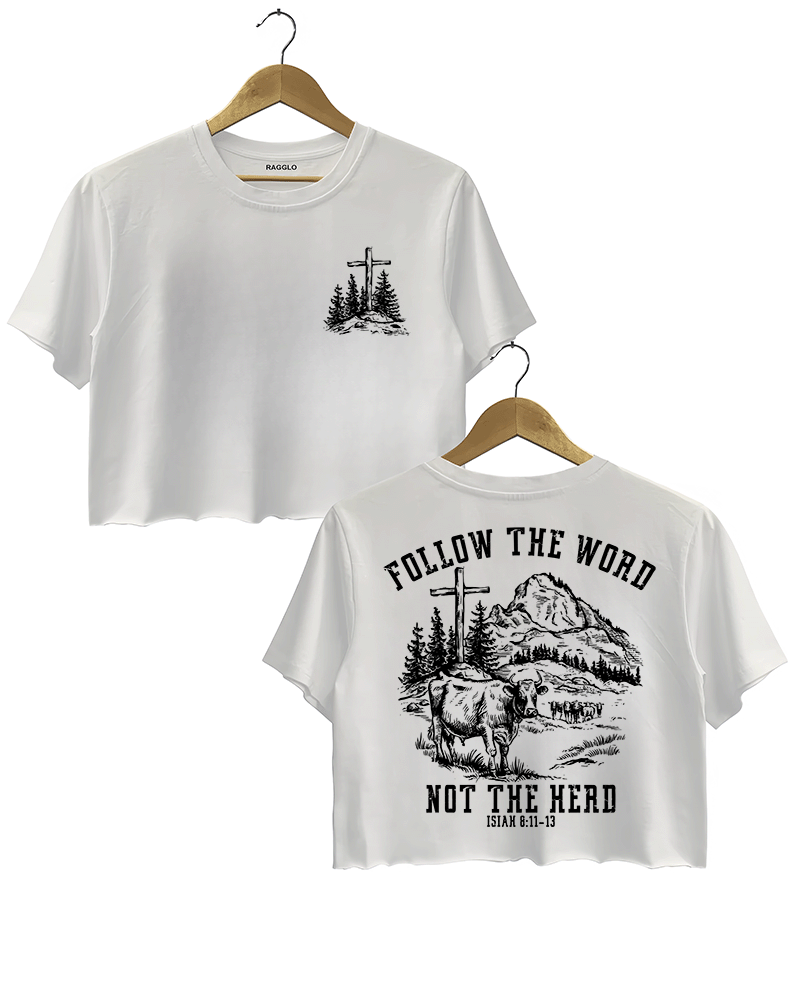 Ragglo white women's cropped T-Shirt featuring a minimalist cross and trees design on the front, and a mountain landscape with cattle, a cross, and trees on the back with the text 'Follow The Word Not The Herd' and 'Isaiah 8:11-13' in a faith-inspired graphic design.