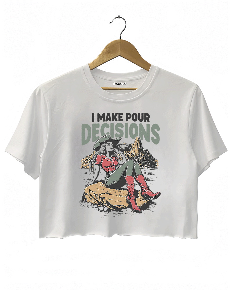 White Ragglo women's crop t-shirt with 'I Make Pour Decisions' text and an illustration of a cowgirl sitting on a rock in a desert landscape.