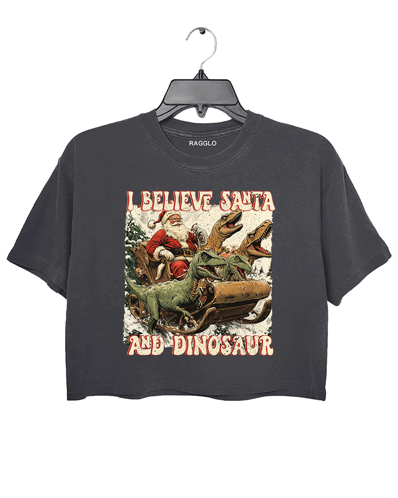 Ragglo dark gray women's crop top with 'I Believe Santa and Dinosaur' text and Santa sleigh pulled by dinosaurs graphic.