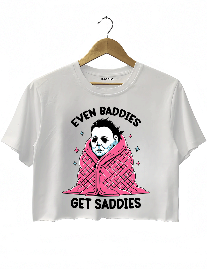 Ragglo white crop top featuring Michael Myers wrapped in a pink blanket with stars, with 'EVEN BADDIES GET SADDIES' text, perfect for horror movie fans and mental health awareness streetwear.