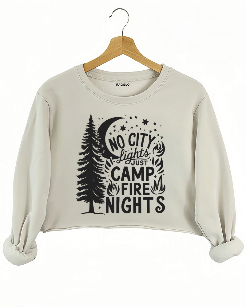 Ragglo beige crop sweatshirt featuring a pine tree, moon, stars, and campfire elements, with 'NO CITY LIGHTS JUST CAMP FIRE NIGHTS' text, perfect for outdoor camping streetwear for nature lovers.