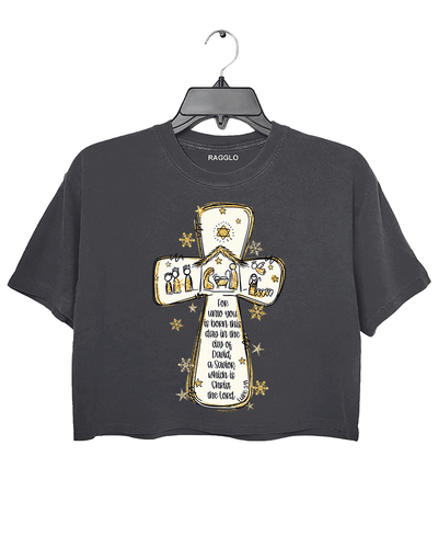 Ragglo dark gray crop top featuring a cross with a nativity scene, stars, and snowflakes, with 'Unto you is born this day in the city of David, a Savior which is Christ the Lord' text, perfect for religious Christmas streetwear.