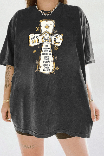 Ragglo dark gray tee featuring a cross with a nativity scene, stars, and snowflakes, with 'Unto you is born this day in the city of David, a Savior which is Christ the Lord' text, perfect for religious Christmas streetwear.