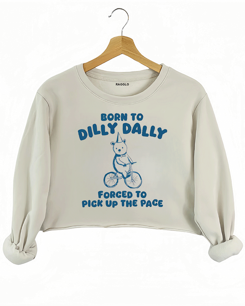 Ragglo beige crop sweatshirt featuring a bear in a party hat riding a bicycle with 'BORN TO DILLY DALLY FORCED TO PICK UP THE PACE' text, perfect for funny casual streetwear.