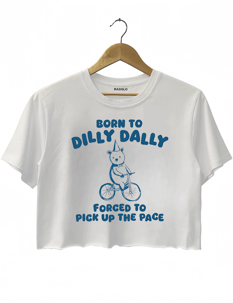 Ragglo white crop top featuring a bear in a party hat riding a bicycle with 'BORN TO DILLY DALLY FORCED TO PICK UP THE PACE' text, perfect for funny casual streetwear.
