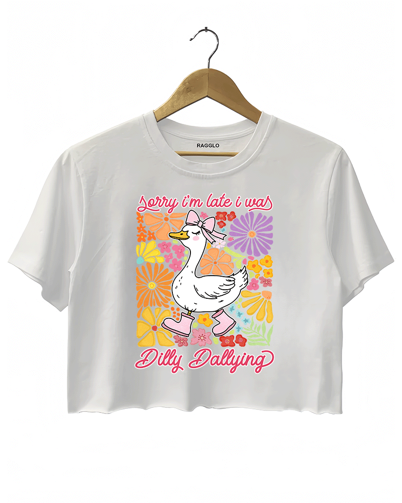 Ragglo white crop top featuring a cute duck in pink rain boots and a bow, surrounded by vibrant flowers, with 'Sorry I'm Late I Was Dilly Dallying' text, perfect for playful floral-inspired casual wear.