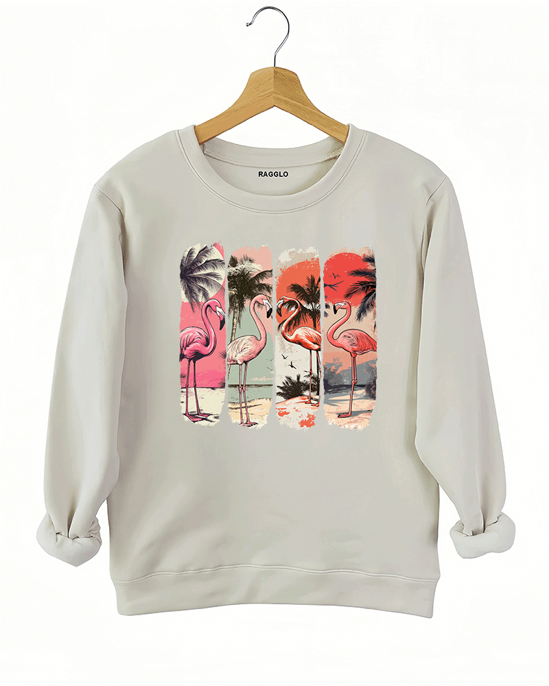 Ragglo beige sweatshirt featuring four pink flamingos on a beach with palm trees and a vibrant sunset, perfect for tropical-inspired casual wear.