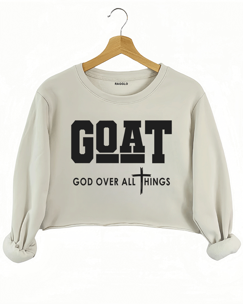 Ragglo beige crop sweatshirt with "GOAT God Over All Things" text and cross symbol in white, featuring a Christian faith-inspired design.