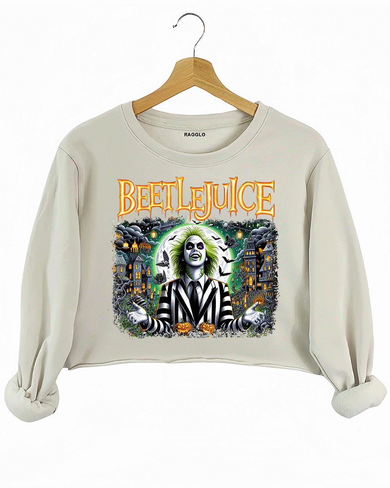 Ragglo beige crop sweatshirt featuring Beetlejuice in a black-and-white striped suit, with a haunted house, bats, and pumpkins in the background, with 'BEETLEJUICE' text, perfect for Halloween streetwear and movie fans.