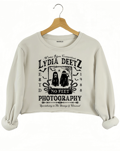 Ragglo beige crop sweatshirt with "Lydia Deetz Photography No Feet" graphic featuring two ghosts, inspired by Beetlejuice with a gothic and supernatural theme.