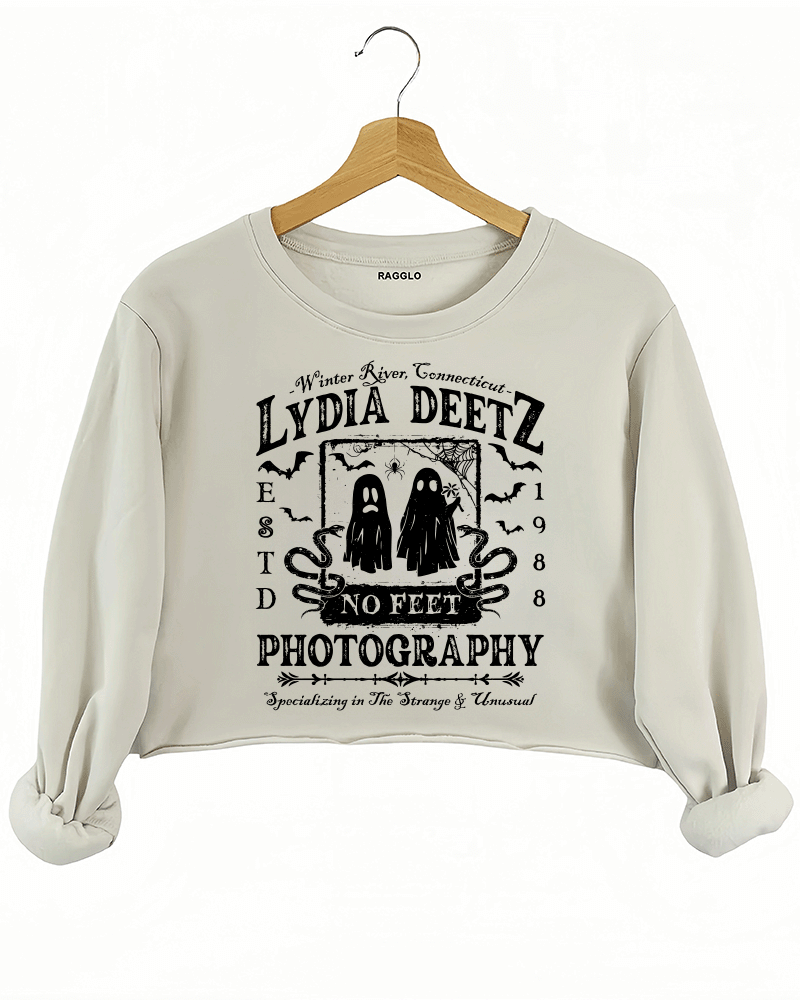 Ragglo beige crop sweatshirt with "Lydia Deetz Photography No Feet" graphic featuring two ghosts, inspired by Beetlejuice with a gothic and supernatural theme.