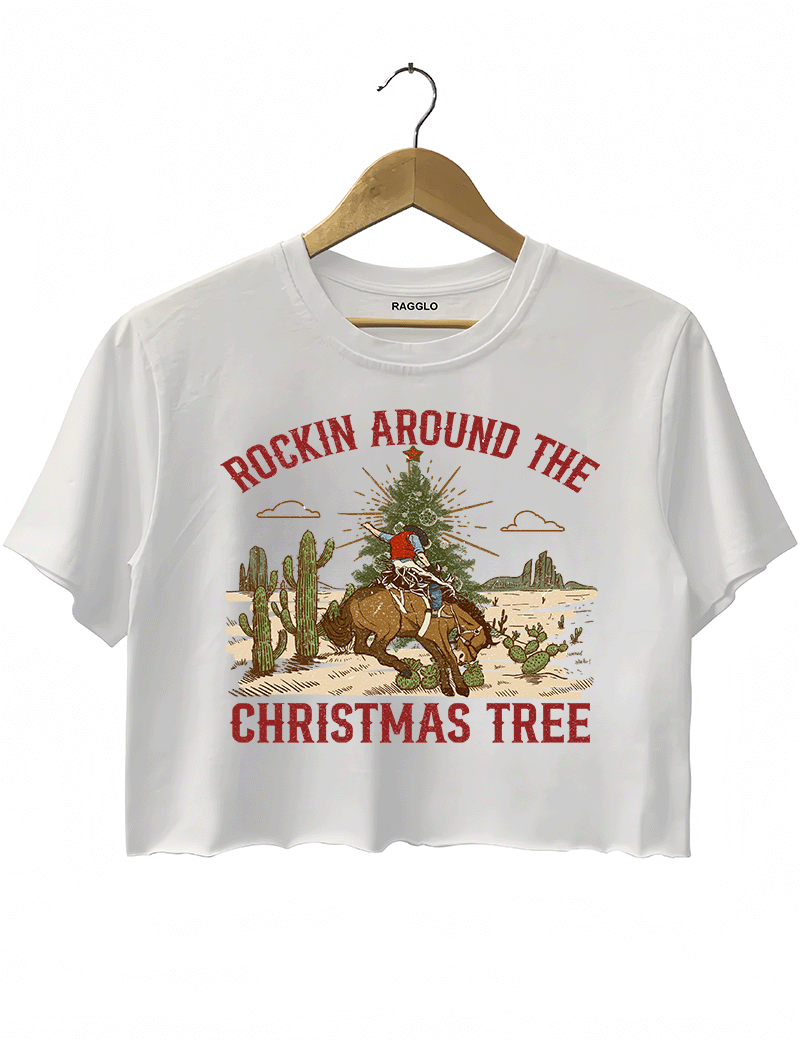 Ragglo white crop top featuring a cowboy riding a horse with a Christmas tree in a desert scene with cacti, with 'ROCKIN AROUND THE CHRISTMAS TREE' text, perfect for festive western-style streetwear.