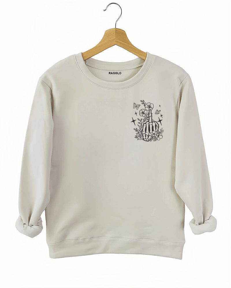 Ragglo beige sweatshirt front view featuring a skeleton hand with a middle finger gesture surrounded by flowers, butterflies, and stars, perfect for bold streetwear style.