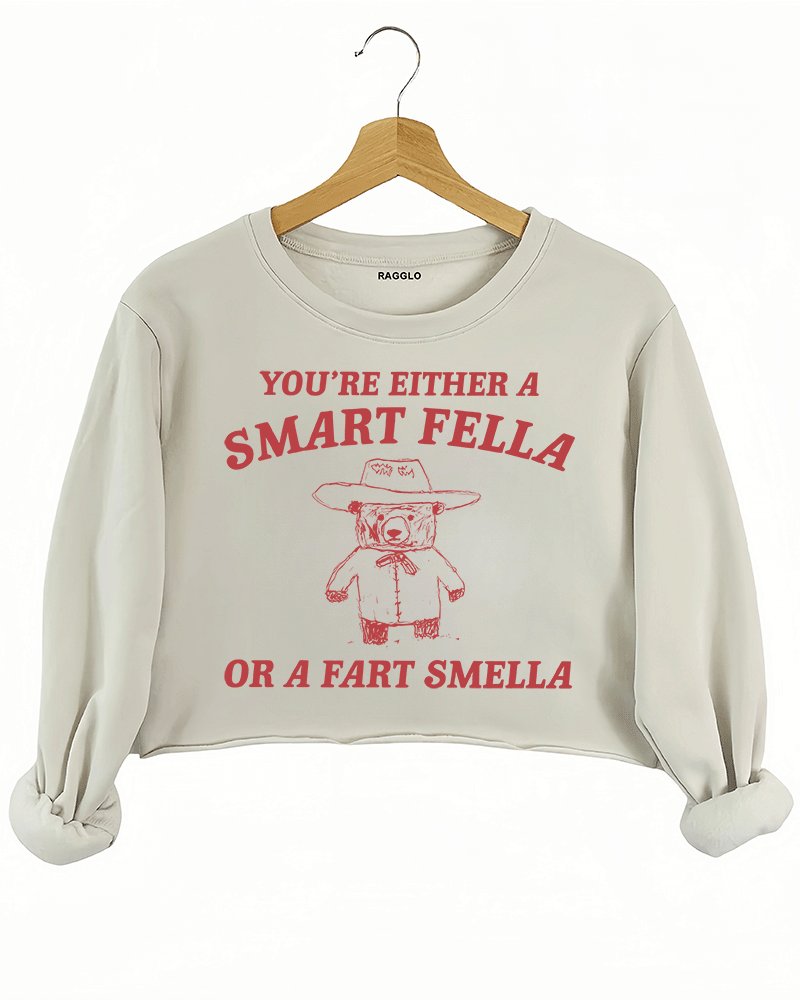 Ragglo beige crop sweatshirt featuring 'YOU’RE EITHER A SMART FELLA OR A FART SMELLA' text with a bear in a cowboy hat, perfect for casual streetwear and humorous everyday wear.