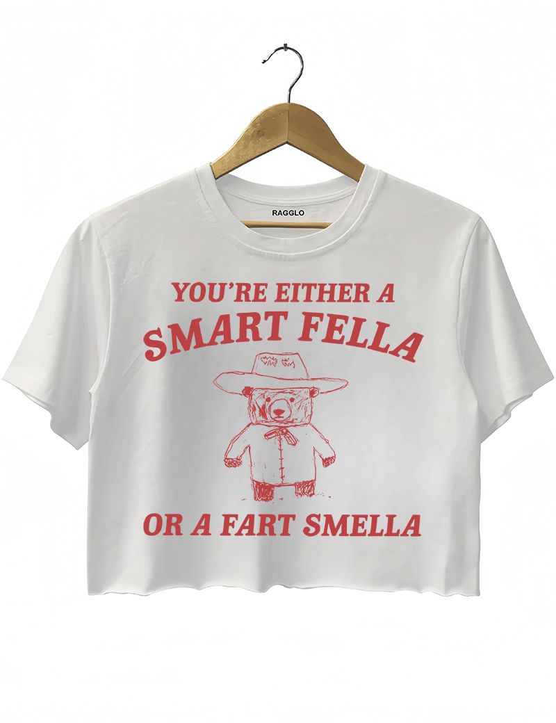 Ragglo white crop top featuring 'YOU’RE EITHER A SMART FELLA OR A FART SMELLA' text with a bear in a cowboy hat, perfect for casual streetwear and humorous everyday wear.