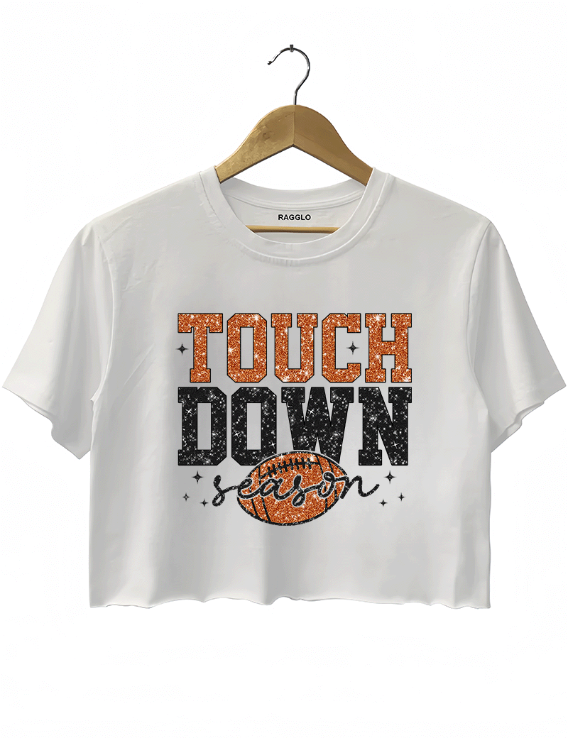 Ragglo white crop top featuring 'TOUCH DOWN' text with a football graphic and 'season' script, accented by stars, perfect for football fans and game day streetwear.