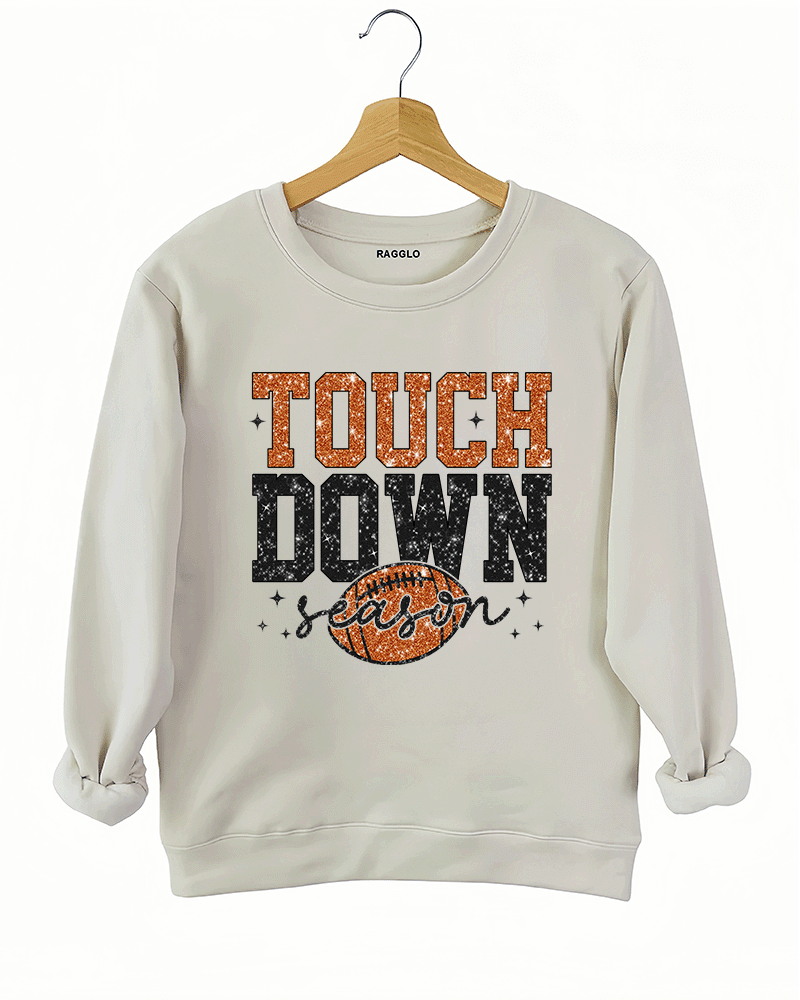 Ragglo beige sweatshirt featuring 'TOUCH DOWN' text with a football graphic and 'season' script, accented by stars, perfect for football fans and game day streetwear.