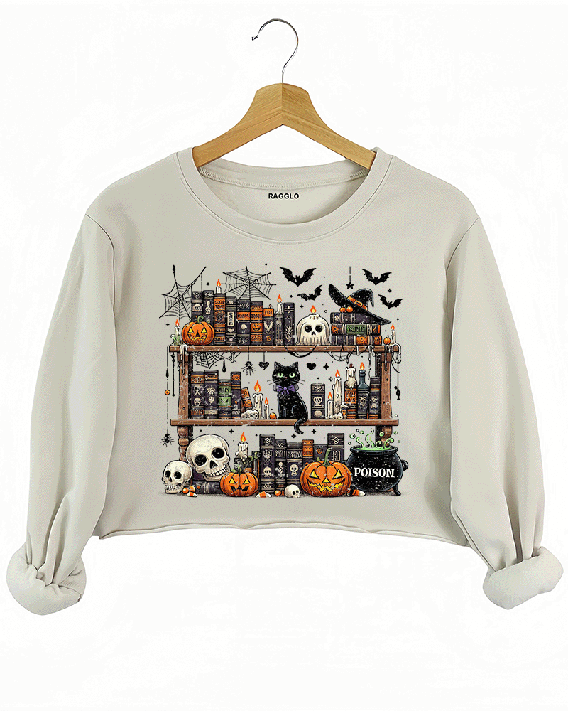 Ragglo beige crop sweatshirt featuring a spooky bookshelf with magic books, pumpkins, skulls, a black cat, and a 'POISON' potion bottle, accented by bats and spiderwebs, perfect for Halloween streetwear and witchy vibes.