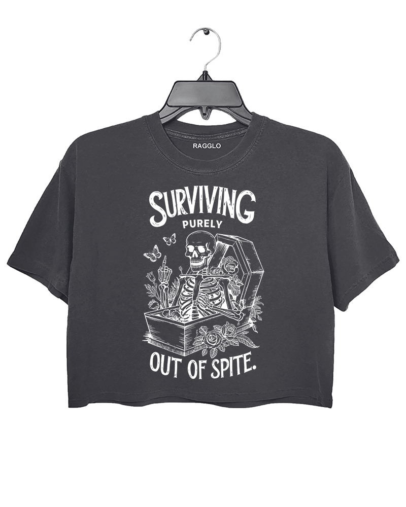 Dark gray crop top featuring a skeleton sitting in a coffin with roses, butterflies, and candles, alongside the humorous text 'Surviving Purely Out of Spite,' available on Ragglo.
