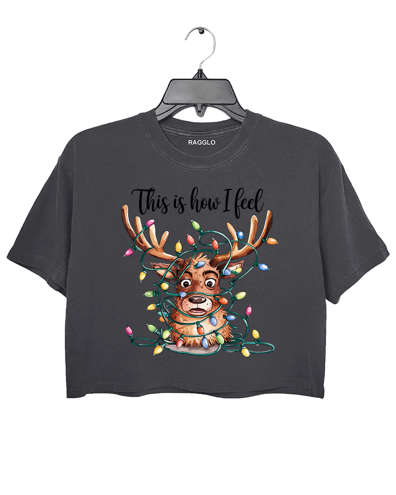 Dark gray crop top featuring a cartoon reindeer tangled in colorful Christmas lights with a humorous expression, accompanied by the text 'This is how I feel,' available on Ragglo.