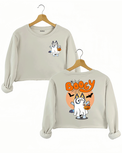 Ragglo beige crop sweatshirt with a Halloween-inspired design featuring a cartoon cat dressed as a ghost. The character is holding a candy bucket, and 'BOOEY' appears in bright orange letters, with bats and spiderwebs in the background.