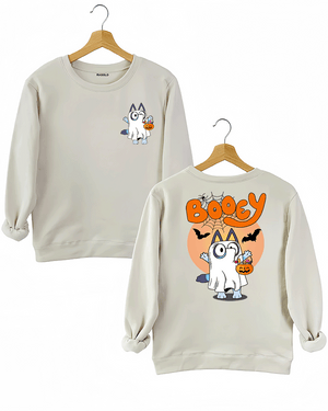 Ragglo beige sweatshirt displaying a cute Halloween-themed cartoon graphic of a cat dressed as a ghost with a pumpkin-shaped candy bucket. The design includes the word 'BOOEY' in bold orange with bats and spiderwebs in the backdrop.