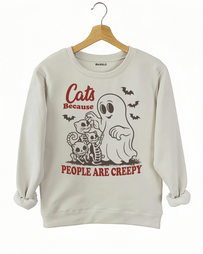 Cats Because People Are Creepy Halloween graphic with a ghost petting skeleton cats, bats flying around, printed on a beige sweatshirt available at Ragglo.