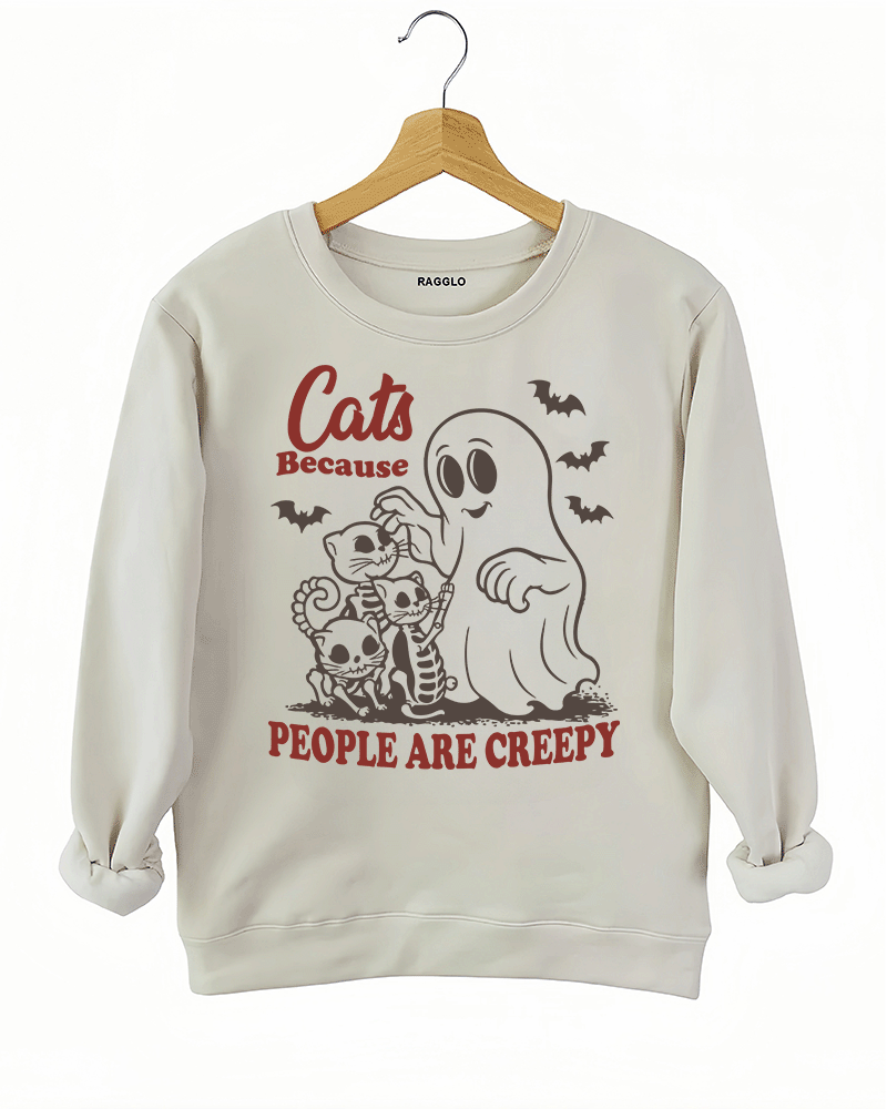 Cats Because People Are Creepy Halloween graphic with a ghost petting skeleton cats, bats flying around, printed on a beige sweatshirt available at Ragglo.