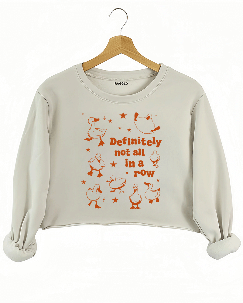 Beige crop sweatshirt featuring the 'Definitely Not All in a Row' graphic, displaying scattered ducks with bold text, giving off a humorous and carefree style.