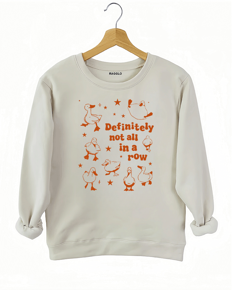 Beige sweatshirt with the 'Definitely Not All in a Row' design, showing playful ducks in disarray alongside bold text, adding a quirky, fun touch to any outfit.