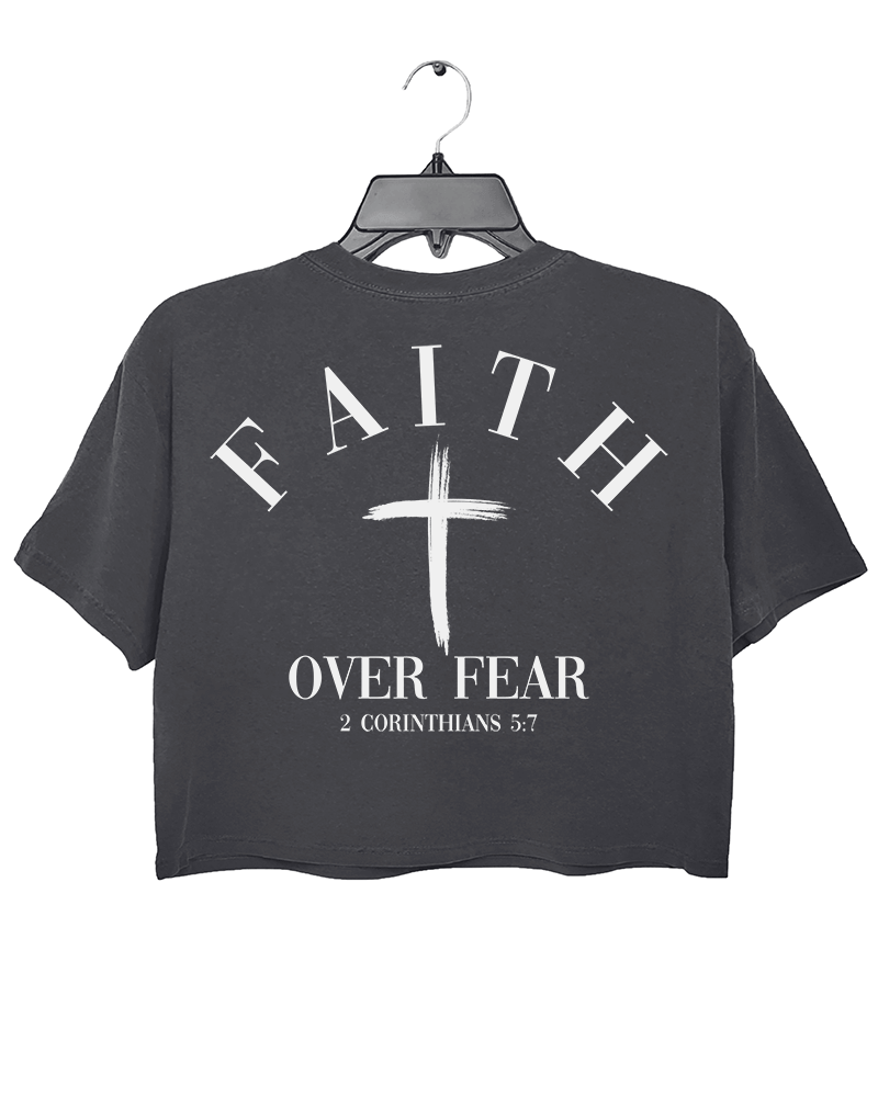 Dark gray Ragglo crop top with "Faith Over Fear" and "2 Corinthians 5:7" text on the back, featuring a prominent white cross design.