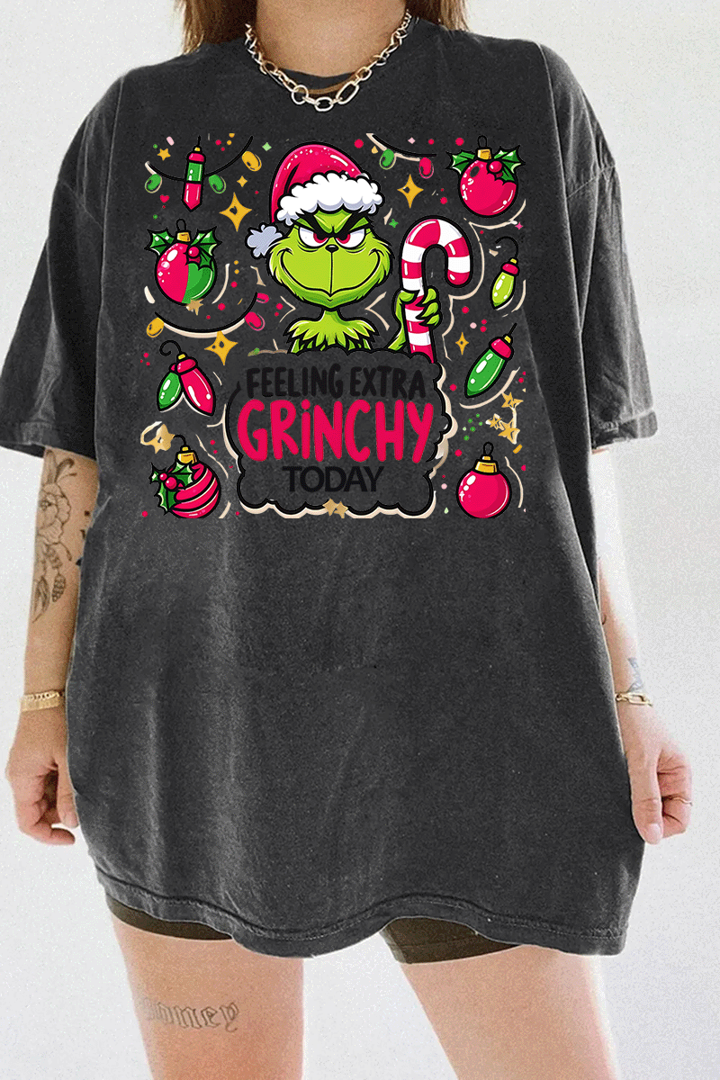 Dark gray T-shirt displaying the Grinch holding a candy cane and surrounded by bright Christmas lights and ornaments, perfect for a fun holiday look, available on Ragglo.