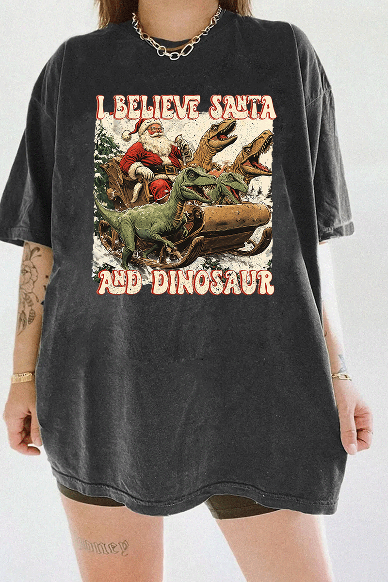 Santa Claus in a sleigh led by dinosaurs, captioned 'I Believe in Santa and Dinosaur' on a dark gray T-shirt, available on Ragglo.