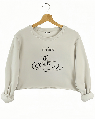 Beige crop sweatshirt showcasing a hand giving a thumbs-up from beneath water, highlighting the contrast between inner difficulties and the appearance of being 'fine.'