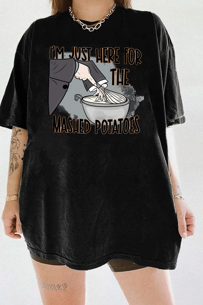Funny black t-shirt with "I'm Just Here for the Mashed Potatoes" text and a hand mixing mashed potatoes graphic, perfect for Thanksgiving or food lovers.

