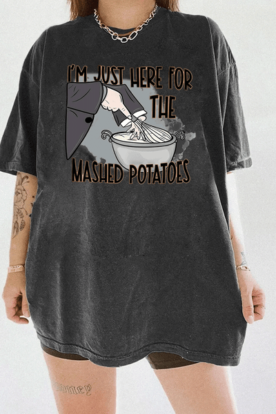 Funny dark gray t-shirt with "I'm Just Here for the Mashed Potatoes" text and a hand mixing mashed potatoes graphic, perfect for Thanksgiving or food lovers.

