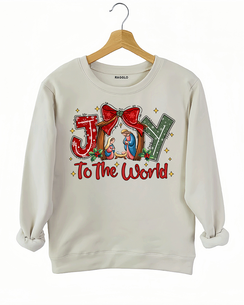 Religious Christmas design with nativity scene and 'Joy to the World' text on a beige sweatshirt, available on Ragglo.