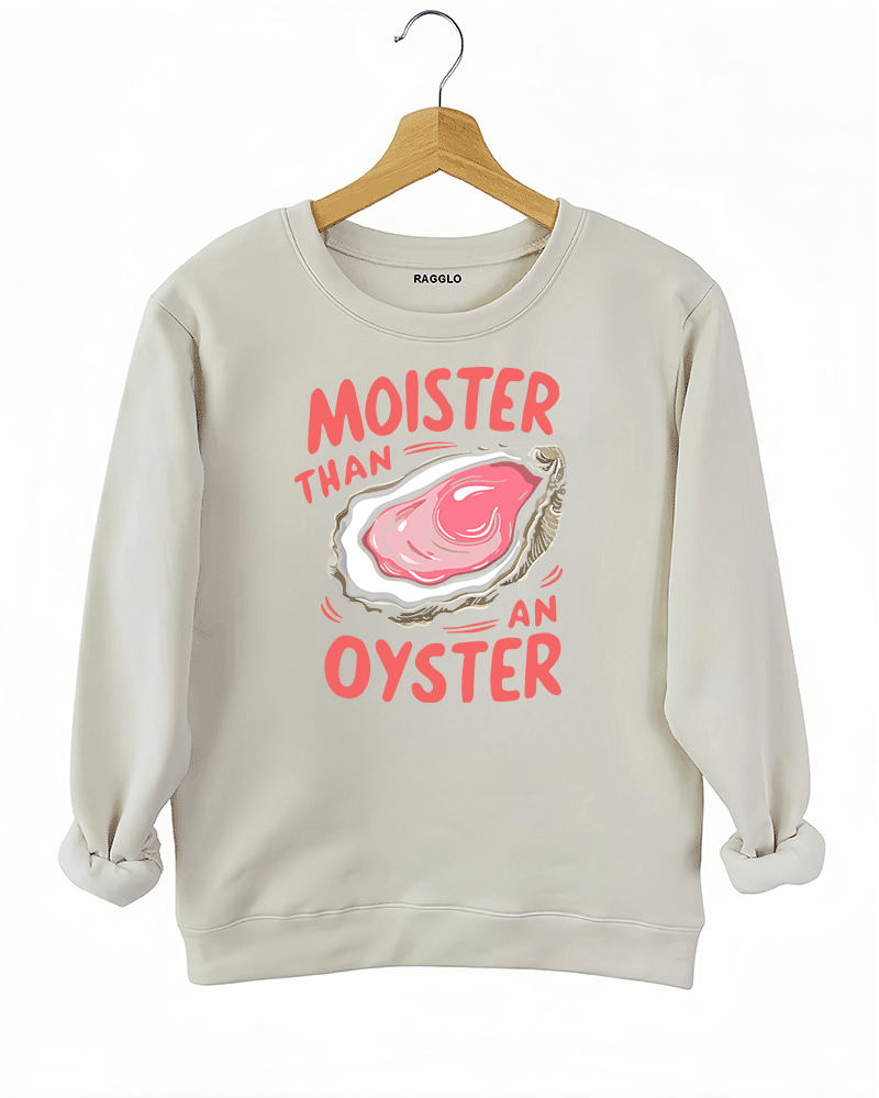 Beige sweatshirt displaying the 'Moister than an Oyster' graphic design, featuring a plump oyster and bold playful text, offering a humorous and quirky statement.