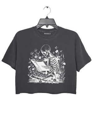 Ragglo dark gray crop top with skeleton reading book graphic surrounded by flowers and butterflies.

