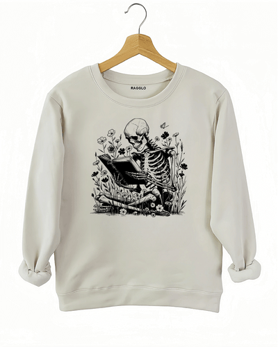 Ragglo beige sweatshirt with skeleton reading book graphic surrounded by flowers and butterflies.

