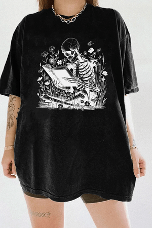 Ragglo black t-shirt with skeleton reading book graphic surrounded by flowers and butterflies.

