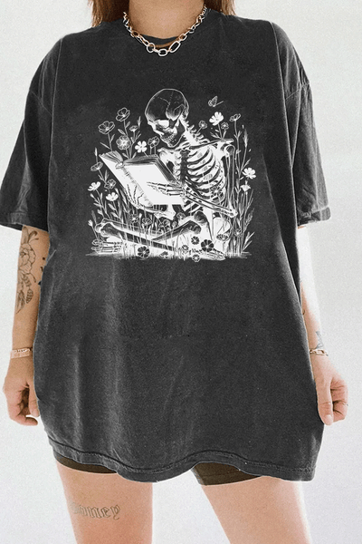 Ragglo dark gray t-shirt with skeleton reading book graphic surrounded by flowers and butterflies.

