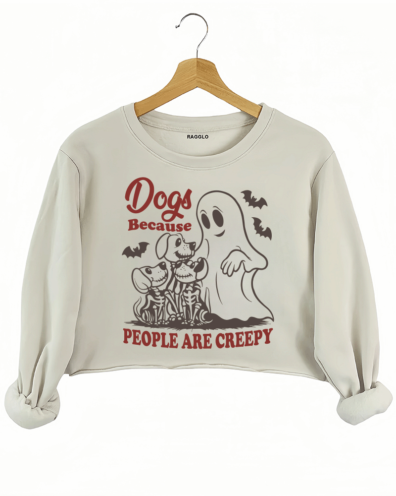 Ragglo beige women's crop sweatshirt featuring three skeleton dogs, a playful ghost, and bats with the humorous text 'Dogs Because People Are Creepy' in a spooky design.