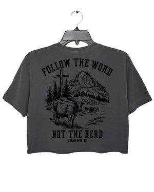 Ragglo dark gray women's crop top back featuring a mountain landscape with cattle, a cross, and trees, and the text 'Follow The Word Not The Herd' and 'Isaiah 8:11-13' in a spiritual graphic design.