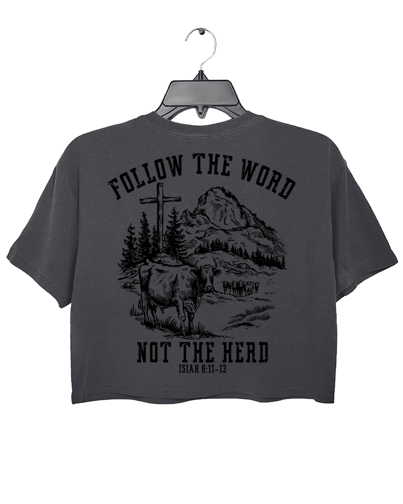 Ragglo dark gray women's crop top back featuring a mountain landscape with cattle, a cross, and trees, and the text 'Follow The Word Not The Herd' and 'Isaiah 8:11-13' in a spiritual graphic design.