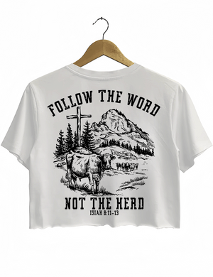 Ragglo white women's cropped T-Shirt back featuring a mountain landscape with cattle, a cross, and trees, and the text 'Follow The Word Not The Herd' and 'Isaiah 8:11-13' in a spiritual graphic design.