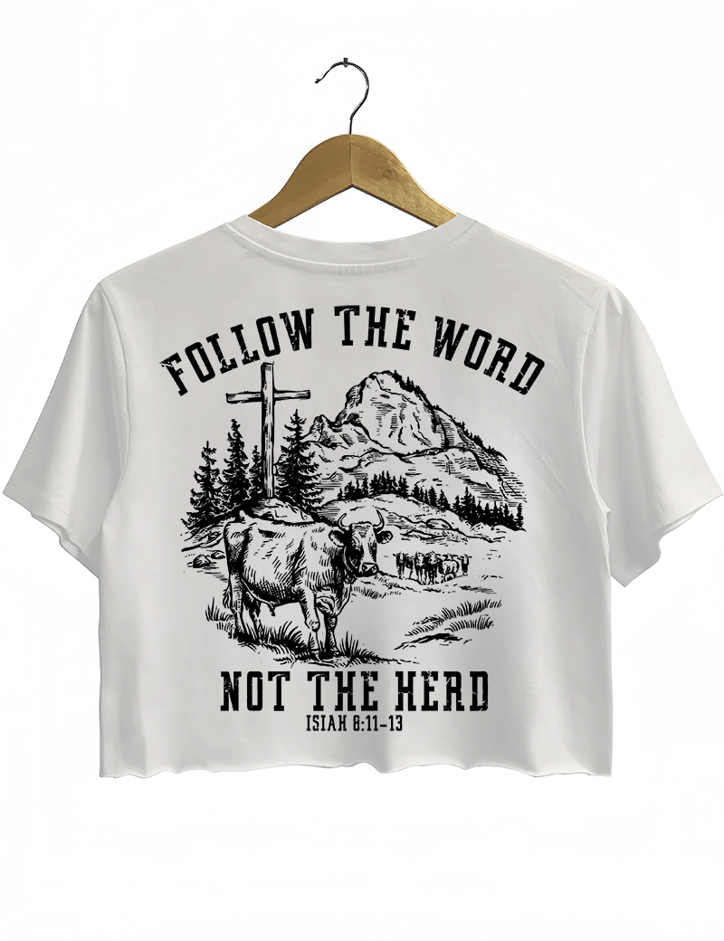 Ragglo white women's cropped T-Shirt back featuring a mountain landscape with cattle, a cross, and trees, and the text 'Follow The Word Not The Herd' and 'Isaiah 8:11-13' in a spiritual graphic design.