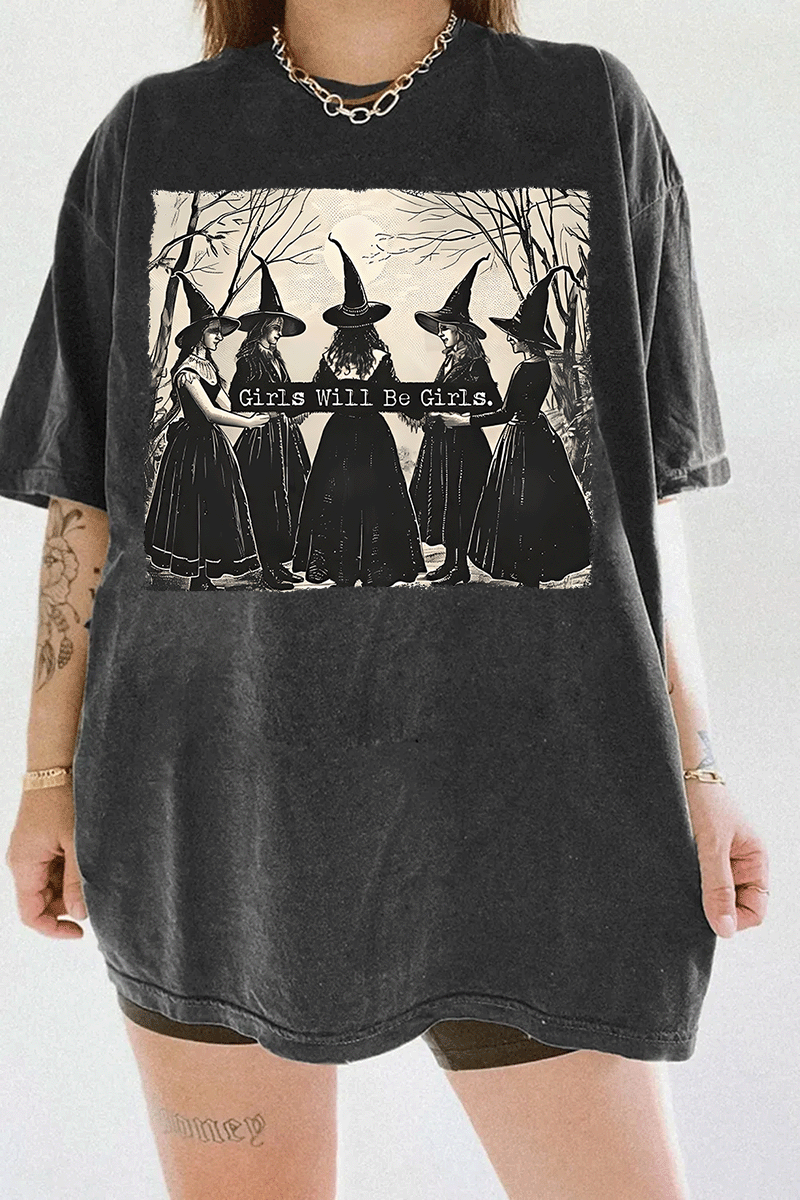 Ragglo dark gray women's T-shirt featuring five witches in black hats holding a sign with the text 'Girls Will Be Girls' in a spooky forest background.