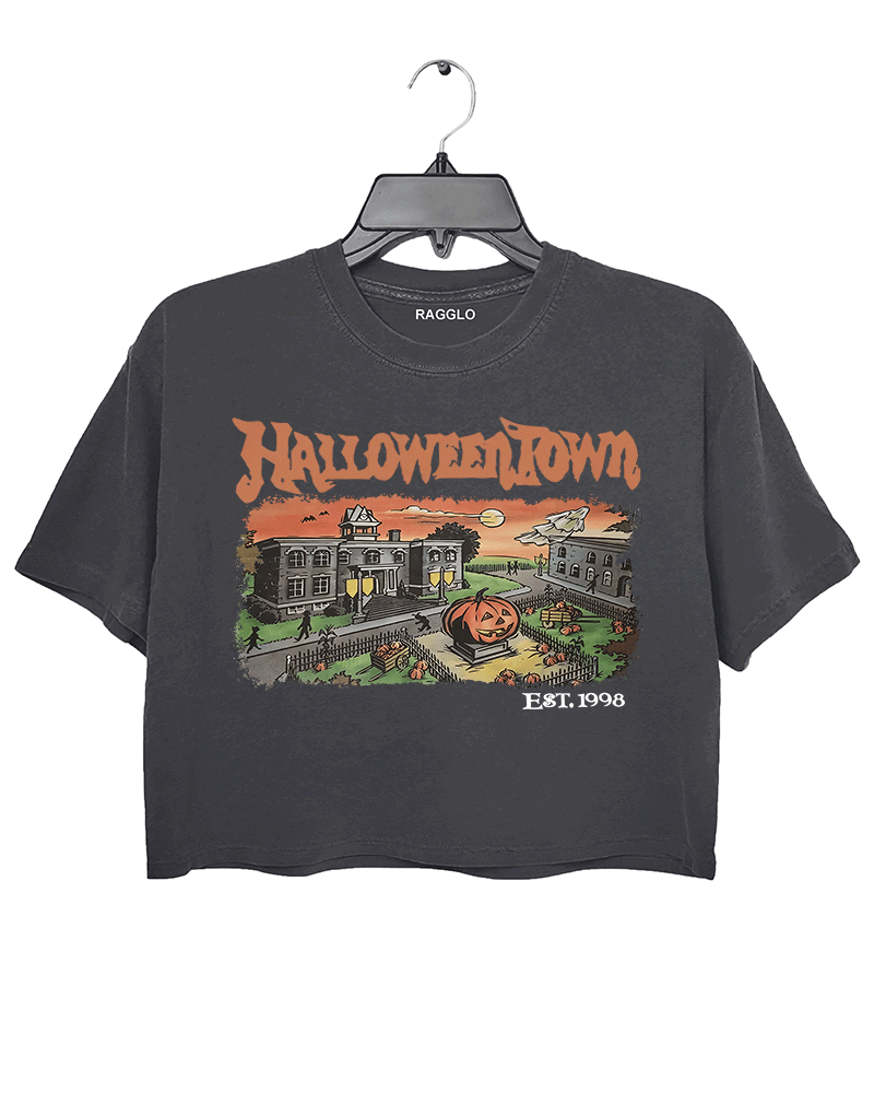 Ragglo dark gray women's crop top featuring a spooky town with a jack-o'-lantern, graveyard, and old houses under a sunset sky with bats, and the text 'Halloween Town Est. 1998' in a retro Halloween graphic design.
