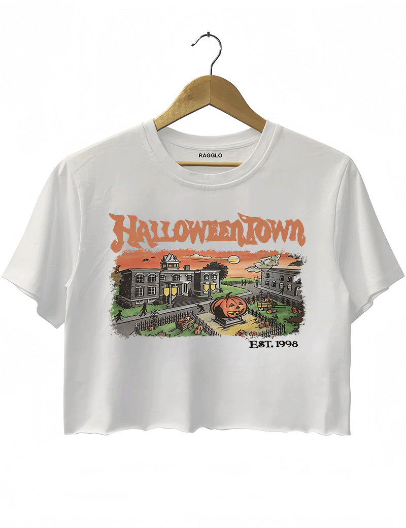 Ragglo white women's crop top featuring a spooky town with a jack-o'-lantern, graveyard, and old houses under a sunset sky with bats, and the text 'Halloween Town Est. 1998' in a retro Halloween graphic design.